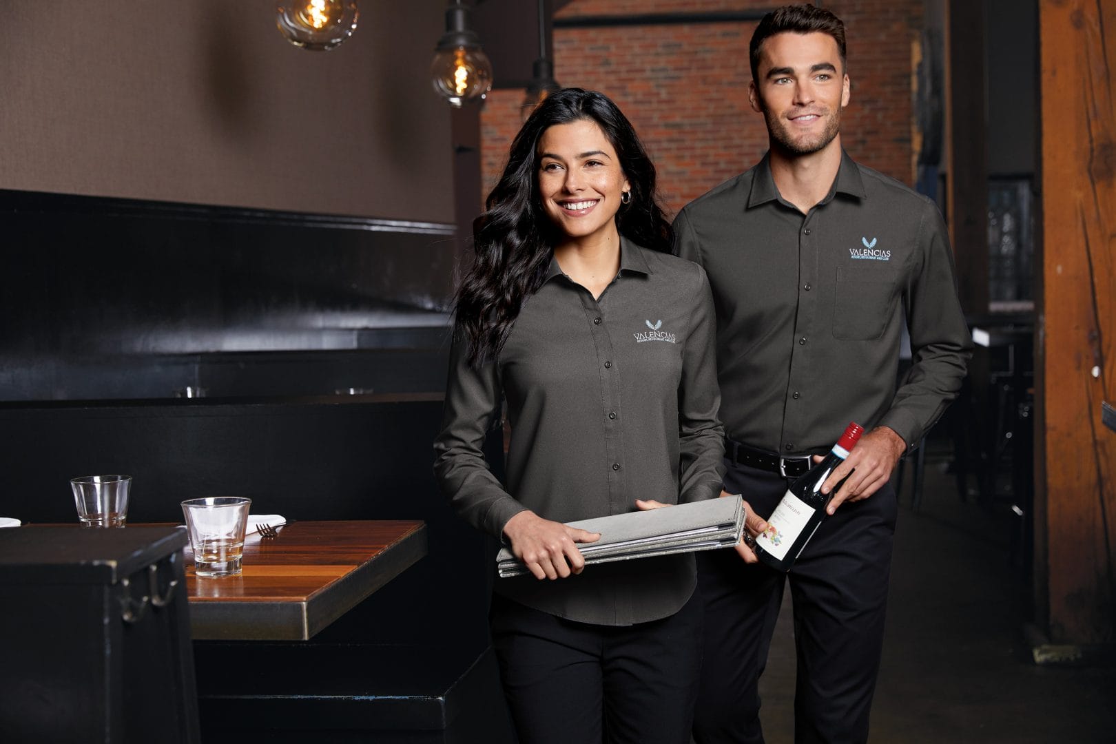Restaurant staff in branded uniforms with embroidered logos and aprons.”