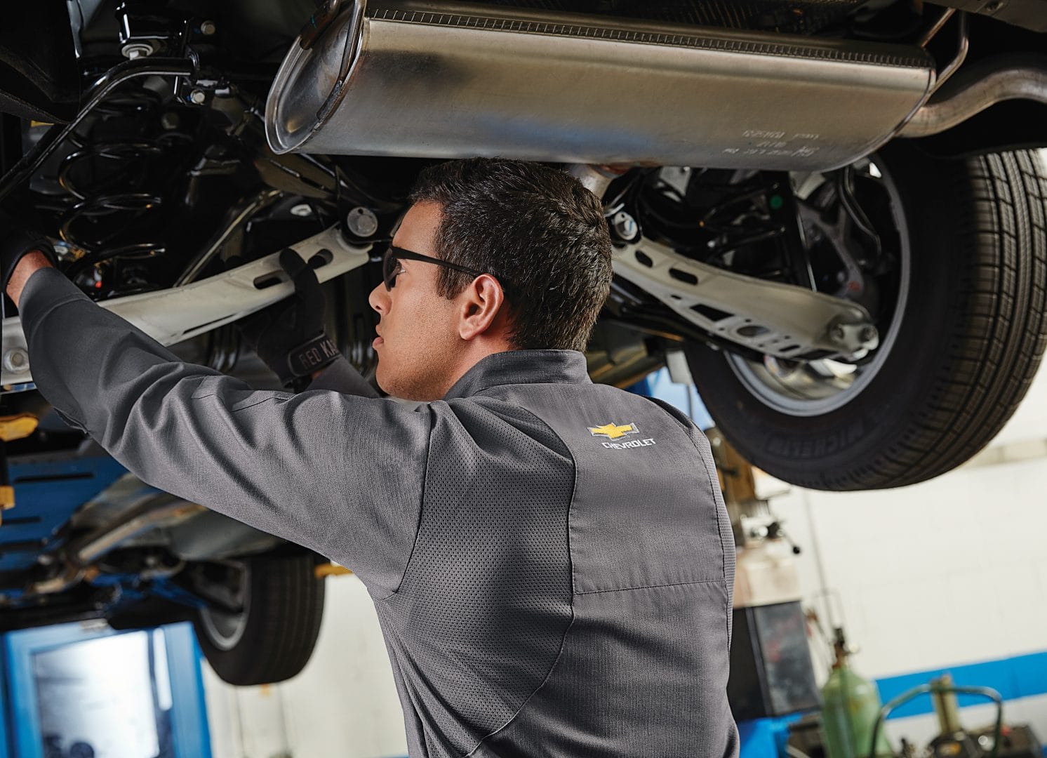 Automotive Technician working on a car in his rented uniform and ppe supplies.