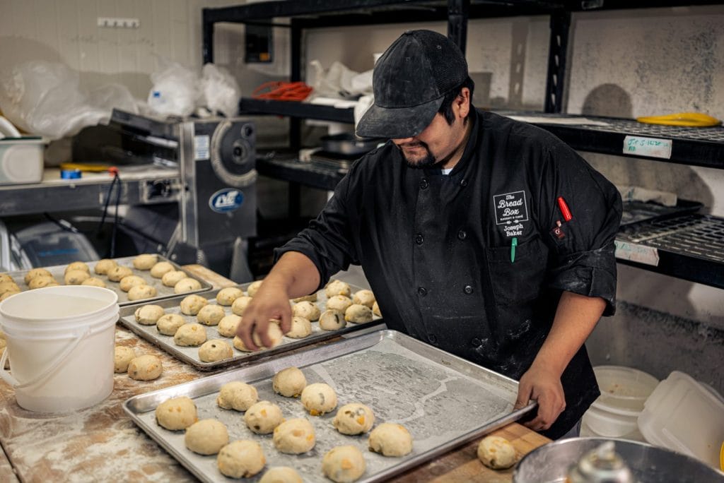 Baker preparing bread in professional, restaurant appropriate attire.