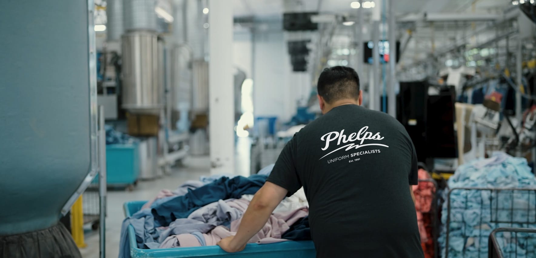 Phelps employee pushing a cart of freshly cleaned uniforms.